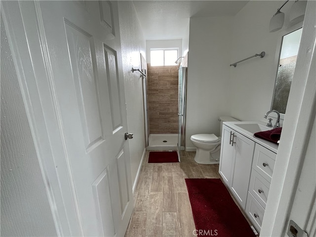 bathroom featuring toilet, vanity, a shower, and wood-type flooring