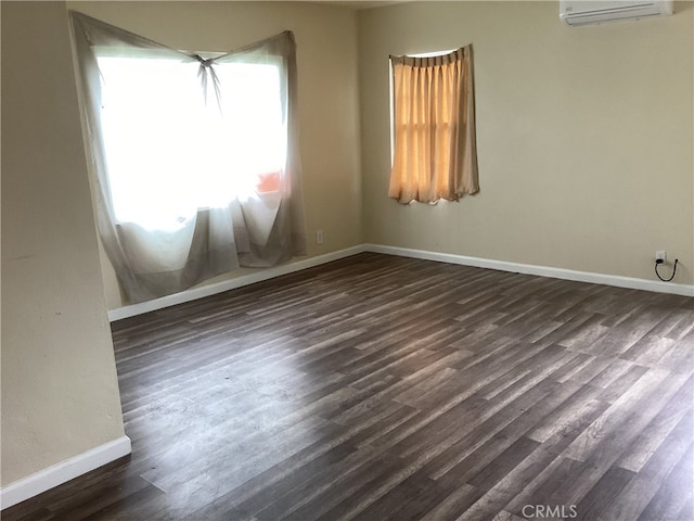 empty room featuring a wall mounted air conditioner and dark wood-type flooring