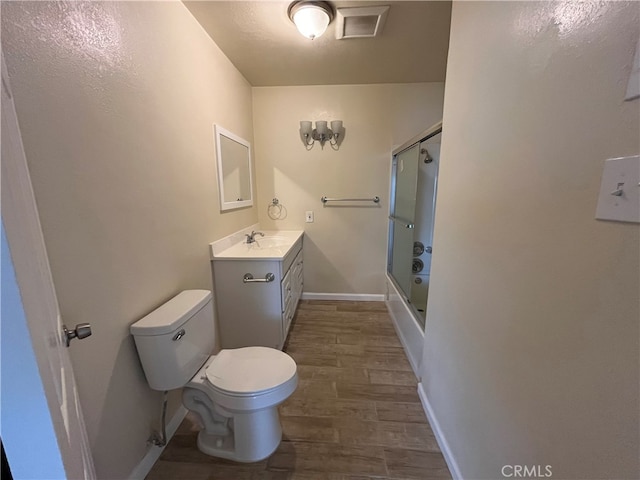 full bathroom with vanity, toilet, wood-type flooring, and enclosed tub / shower combo