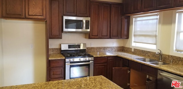 kitchen with light stone countertops, appliances with stainless steel finishes, and sink