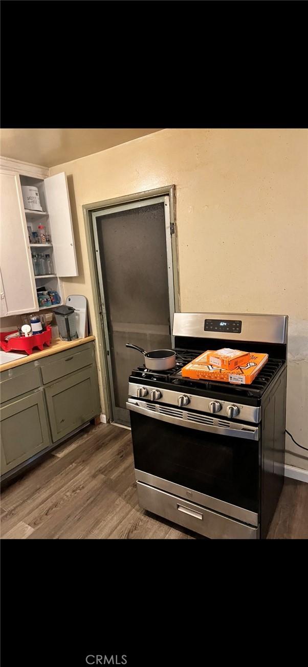 kitchen with stainless steel range with gas cooktop, white cabinets, and wood-type flooring