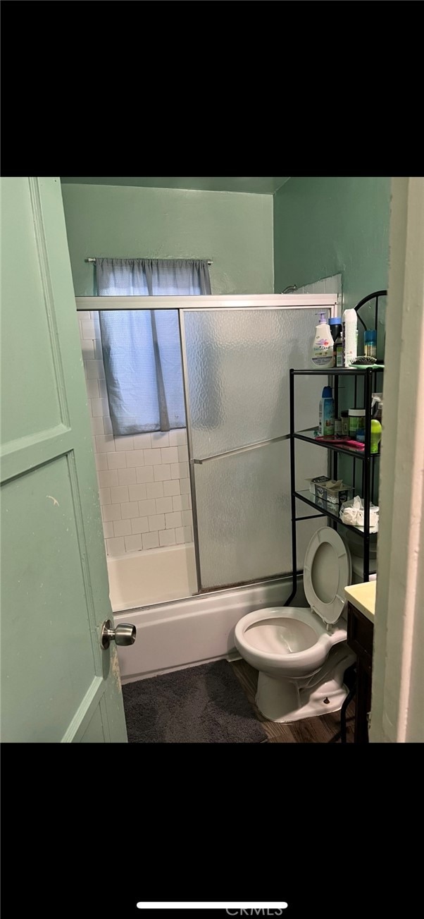 full bathroom featuring vanity, toilet, and enclosed tub / shower combo