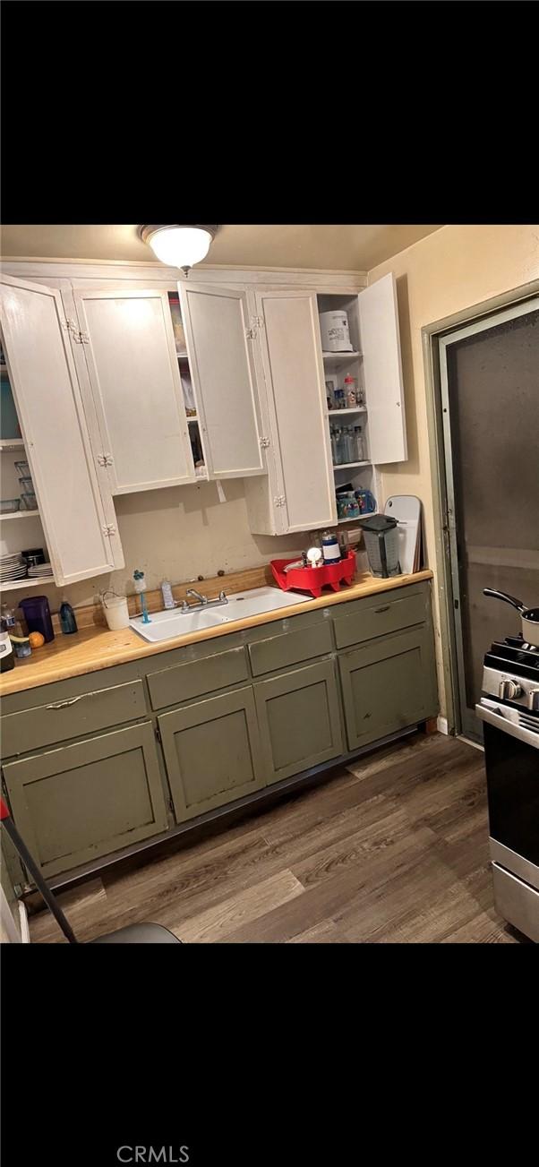 kitchen featuring gas stove, sink, hardwood / wood-style floors, and white cabinets