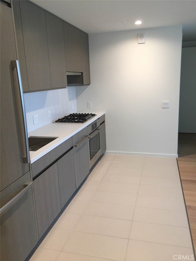 kitchen featuring light tile floors, oven, gray cabinets, and gas cooktop