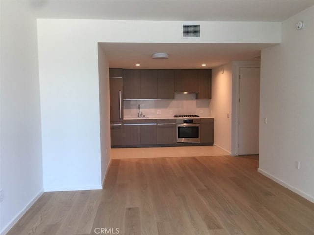 kitchen with oven, light hardwood / wood-style floors, gas stovetop, and sink