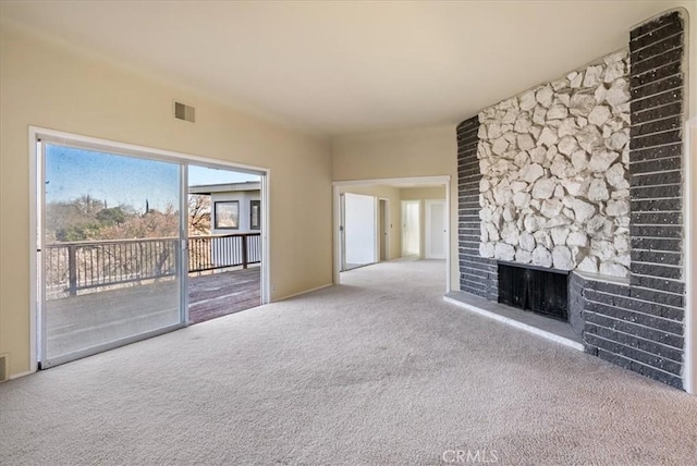 unfurnished living room with light carpet and a stone fireplace