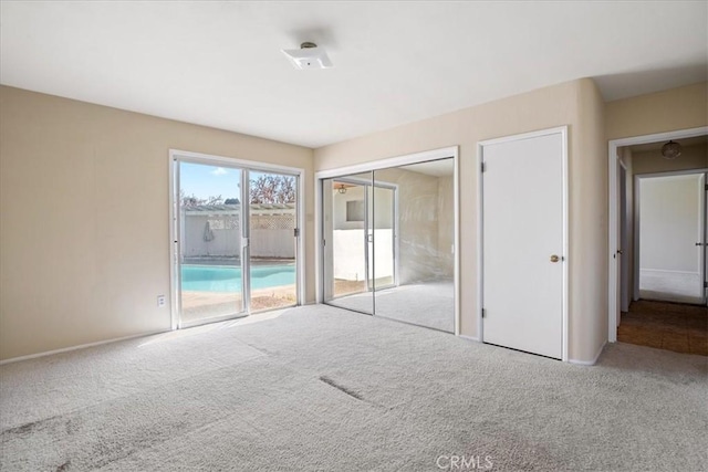 unfurnished bedroom featuring access to exterior, light colored carpet, and a closet