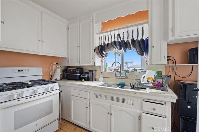 6820 S Van Ness Ave, Los Angeles, CA 90047 - kitchen featuring white range with gas stovetop, white cabinets, light countertops, and tasteful backsplash