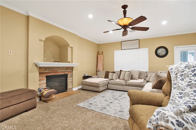 carpeted living room featuring crown molding, a fireplace, and ceiling fan