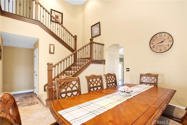 tiled dining area featuring a towering ceiling