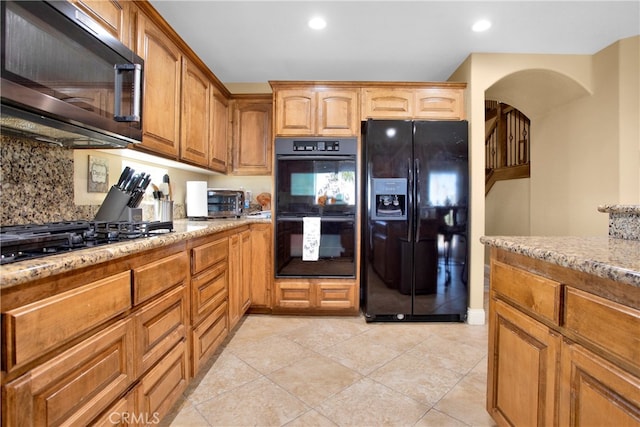 kitchen featuring black appliances, light tile patterned floors, light stone counters, and tasteful backsplash