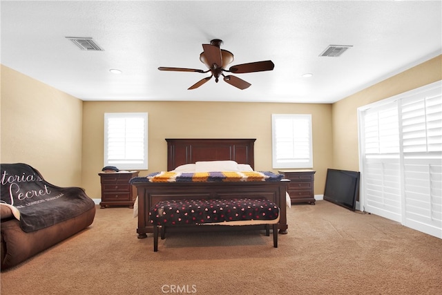 carpeted bedroom featuring ceiling fan, a textured ceiling, and multiple windows