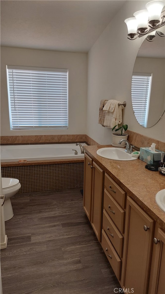 bathroom with vanity, a relaxing tiled tub, radiator heating unit, and hardwood / wood-style floors