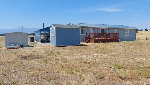 rear view of property featuring a wooden deck, a storage unit, and central air condition unit