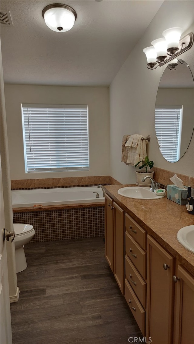 bathroom featuring a bathing tub, hardwood / wood-style floors, radiator heating unit, toilet, and vanity