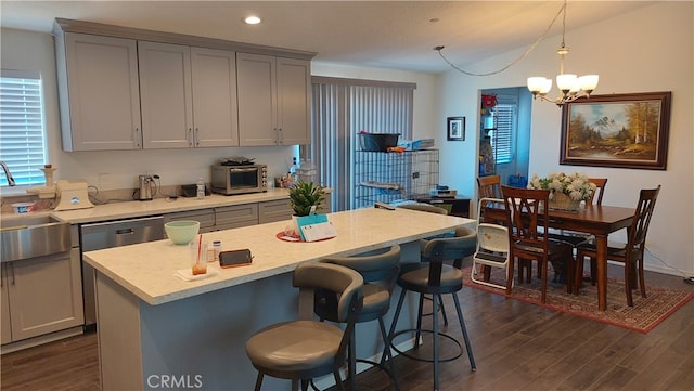 kitchen with a center island, dark hardwood / wood-style flooring, pendant lighting, gray cabinets, and an inviting chandelier