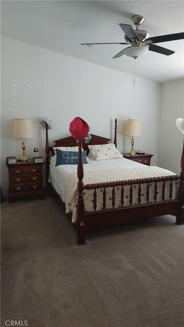 bedroom with dark colored carpet, a textured ceiling, and ceiling fan