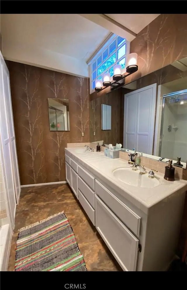 bathroom featuring a shower with shower door and vanity