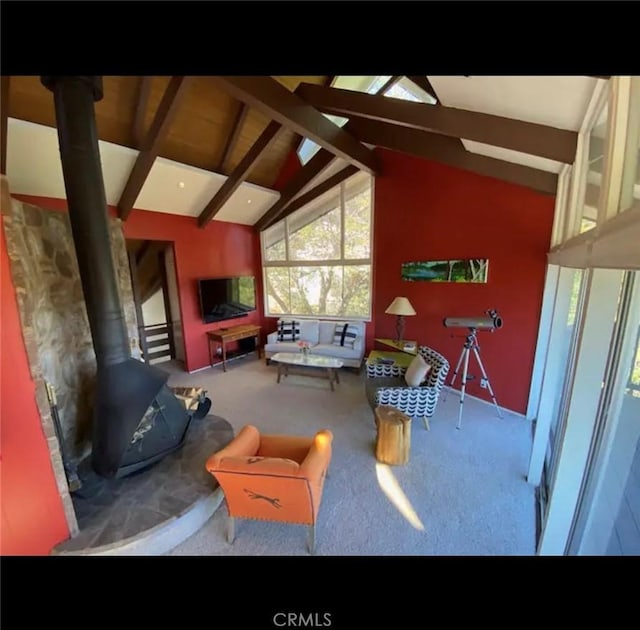 living room with carpet, a wood stove, and lofted ceiling with beams