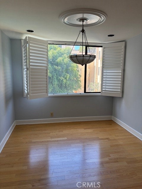 spare room with a notable chandelier and light wood-type flooring