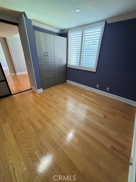 unfurnished bedroom featuring ornamental molding, light hardwood / wood-style flooring, and a closet