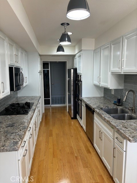 kitchen featuring appliances with stainless steel finishes, light wood-type flooring, sink, and white cabinetry