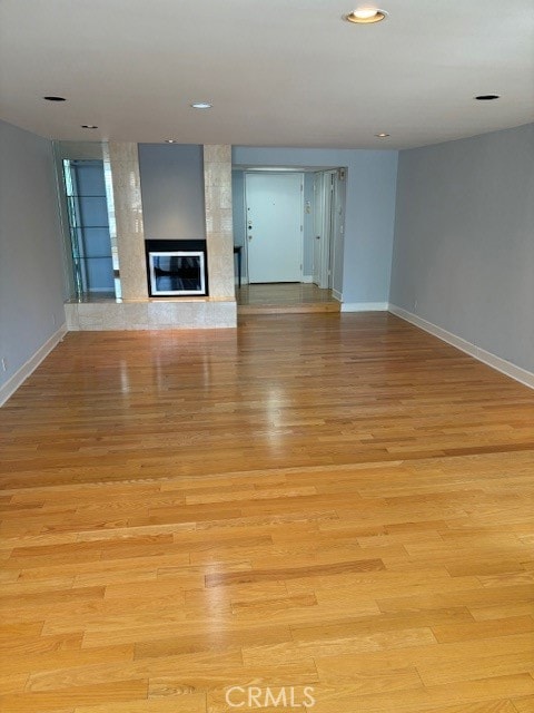 unfurnished living room with a large fireplace and light hardwood / wood-style flooring