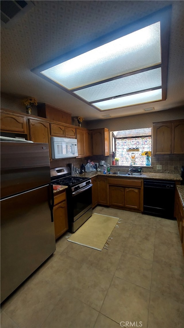 kitchen with sink, backsplash, appliances with stainless steel finishes, and light tile patterned flooring