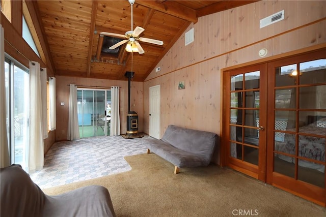 interior space featuring lofted ceiling with beams, a wood stove, ceiling fan, and wooden ceiling