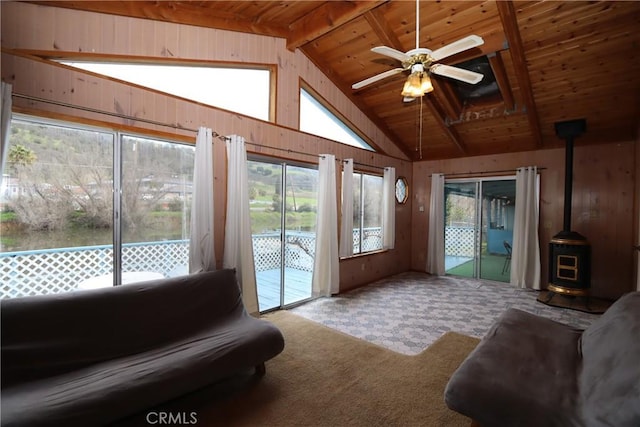 sunroom featuring a wood stove, plenty of natural light, and ceiling fan