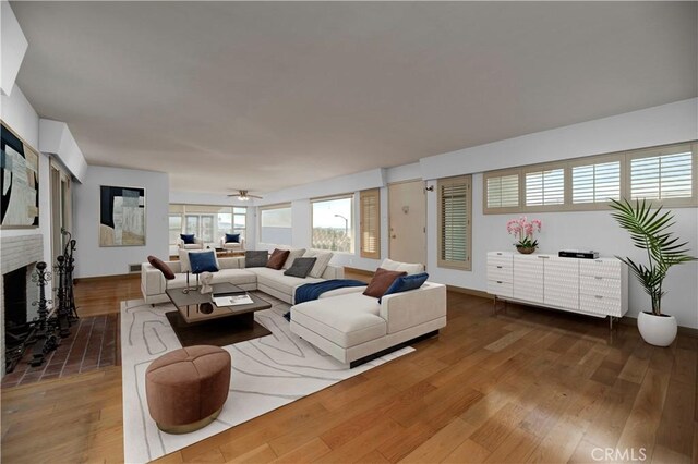 living room featuring a brick fireplace, hardwood / wood-style floors, and ceiling fan