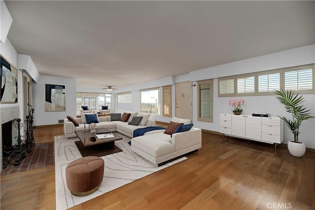 living area with a fireplace, wood finished floors, and a ceiling fan