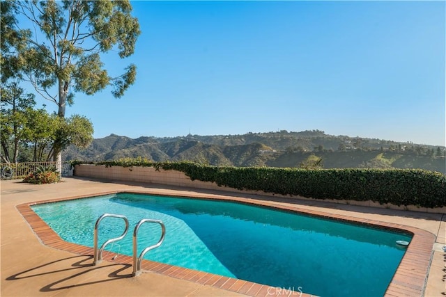 view of swimming pool with a mountain view and a patio area