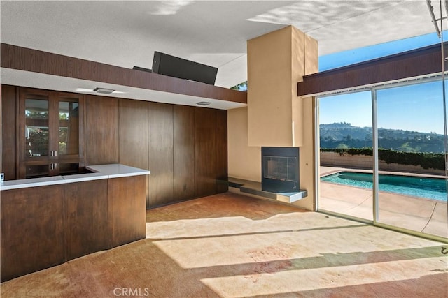 1470 Laurel Way, Beverly Hills, CA 90210 - unfurnished living room featuring carpet floors, a glass covered fireplace, wood walls, and plenty of natural light