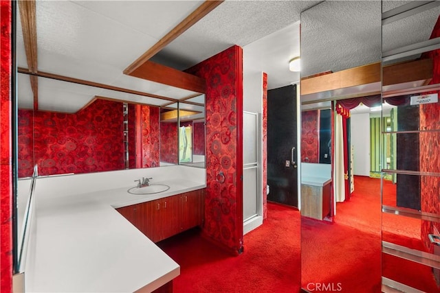 bathroom with a shower with door, vanity, and a textured ceiling