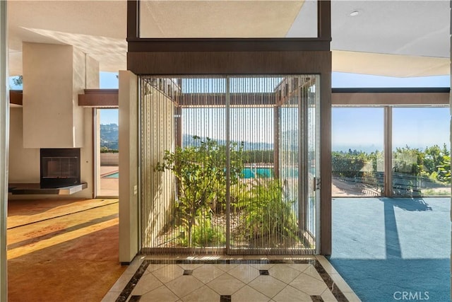 1470 Laurel Way, Beverly Hills, CA 90210 - entryway featuring inlaid floor details, carpet, a glass covered fireplace, and tile patterned floors
