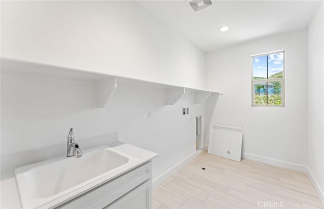 laundry room with hookup for a washing machine, light wood-type flooring, and sink