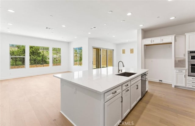 kitchen featuring white cabinets, sink, a kitchen island with sink, and light hardwood / wood-style flooring