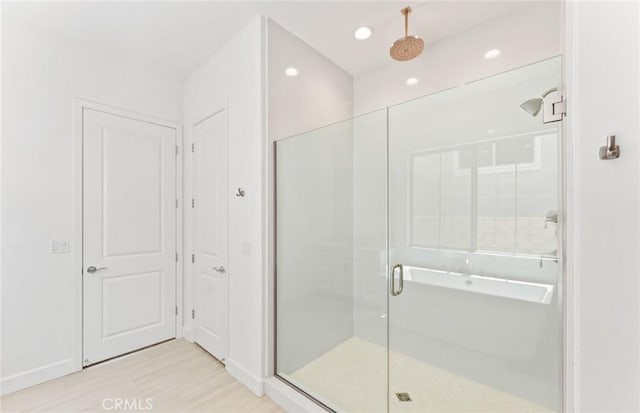 bathroom with wood-type flooring and a shower with shower door