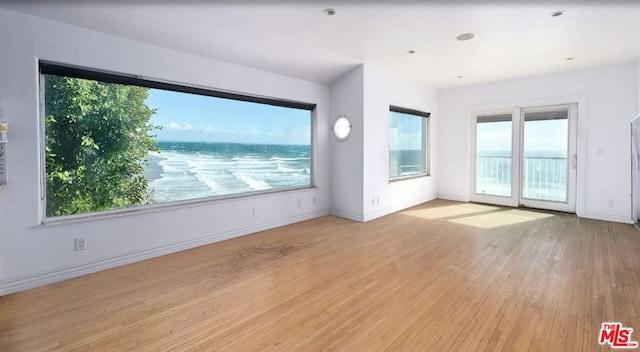 spare room with light hardwood / wood-style floors and a water view