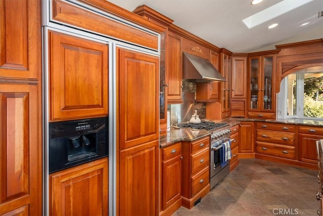 kitchen featuring dark stone countertops, extractor fan, lofted ceiling with skylight, and double oven range