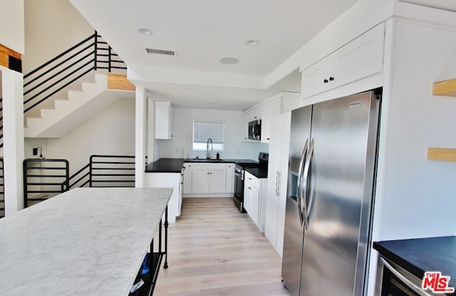 kitchen with white cabinetry, stainless steel appliances, sink, and light wood-type flooring