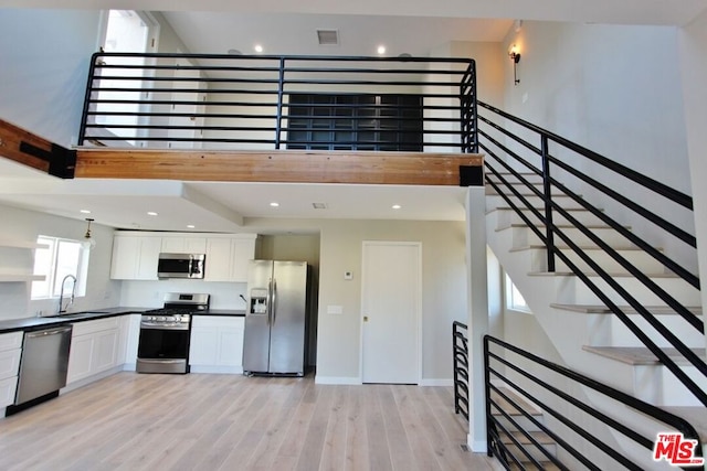 kitchen featuring sink, white cabinetry, light hardwood / wood-style flooring, and stainless steel appliances