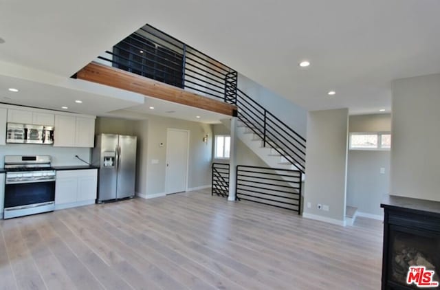 kitchen with appliances with stainless steel finishes, light hardwood / wood-style flooring, and white cabinetry