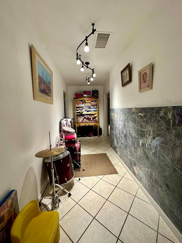 hallway with light tile patterned flooring, track lighting, and tile walls