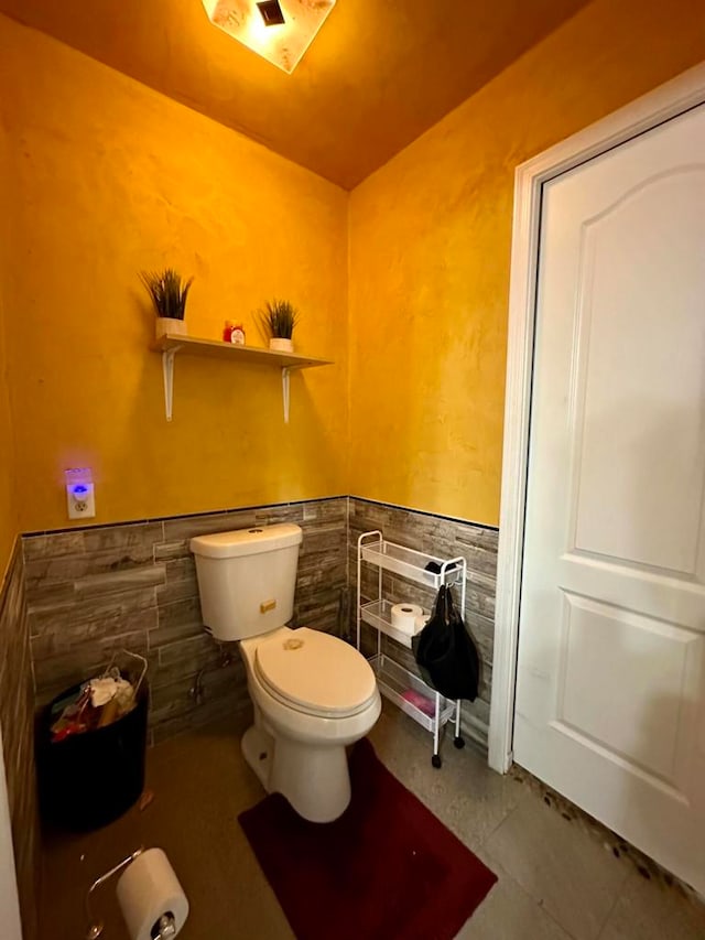 bathroom with tile walls and toilet