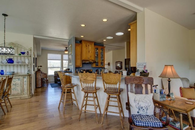 kitchen featuring a kitchen breakfast bar, ceiling fan, hanging light fixtures, and light wood-type flooring