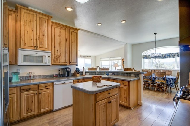 kitchen with a kitchen island, sink, pendant lighting, and white appliances