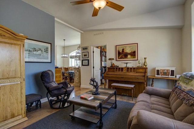 living room featuring lofted ceiling, ceiling fan with notable chandelier, and light hardwood / wood-style floors