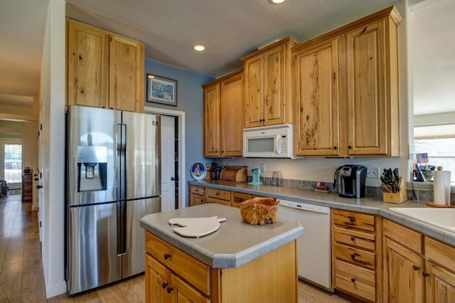 kitchen with white appliances, a center island, sink, and light hardwood / wood-style flooring